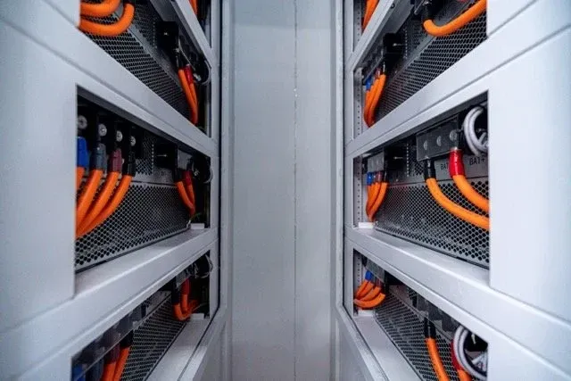 Gangen inne i containeren med batterirack og oransje DC-kabler på begge sider