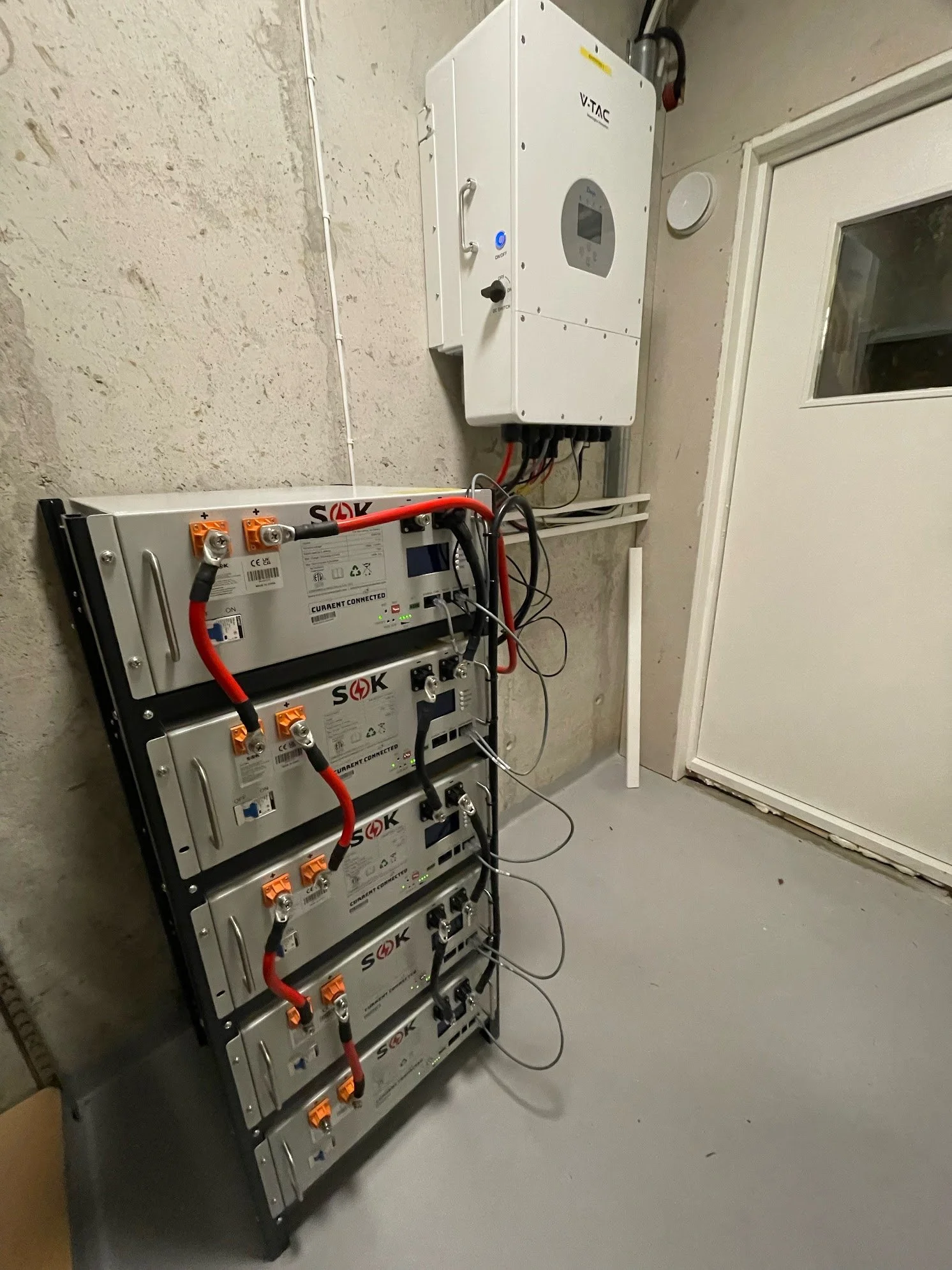 Enebolig med solcellepaneler på taket og batteri med hybridinverter installert innendørs.